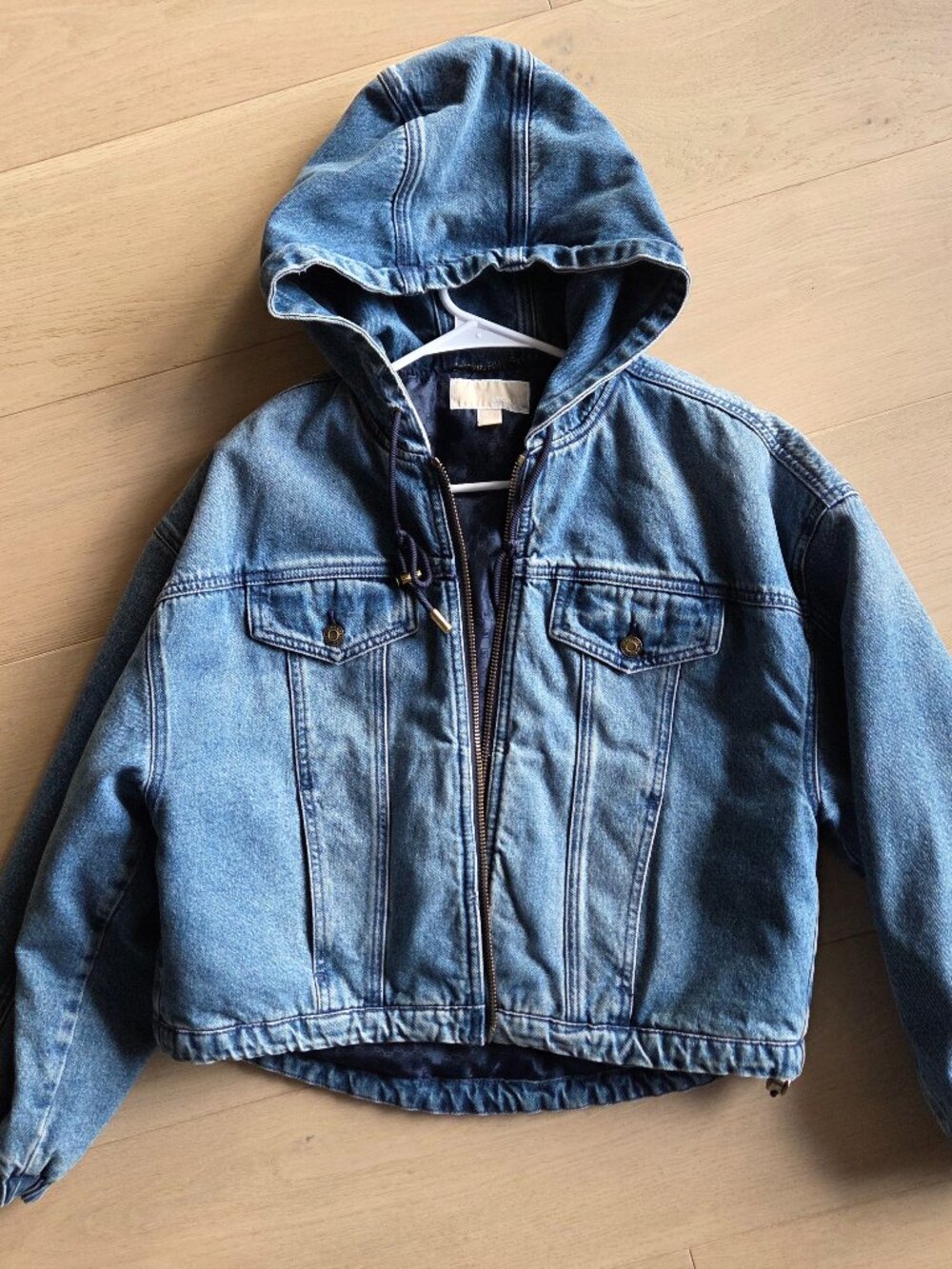 Michael Kors cropped blue denim jacket with hood and zipper closure.
